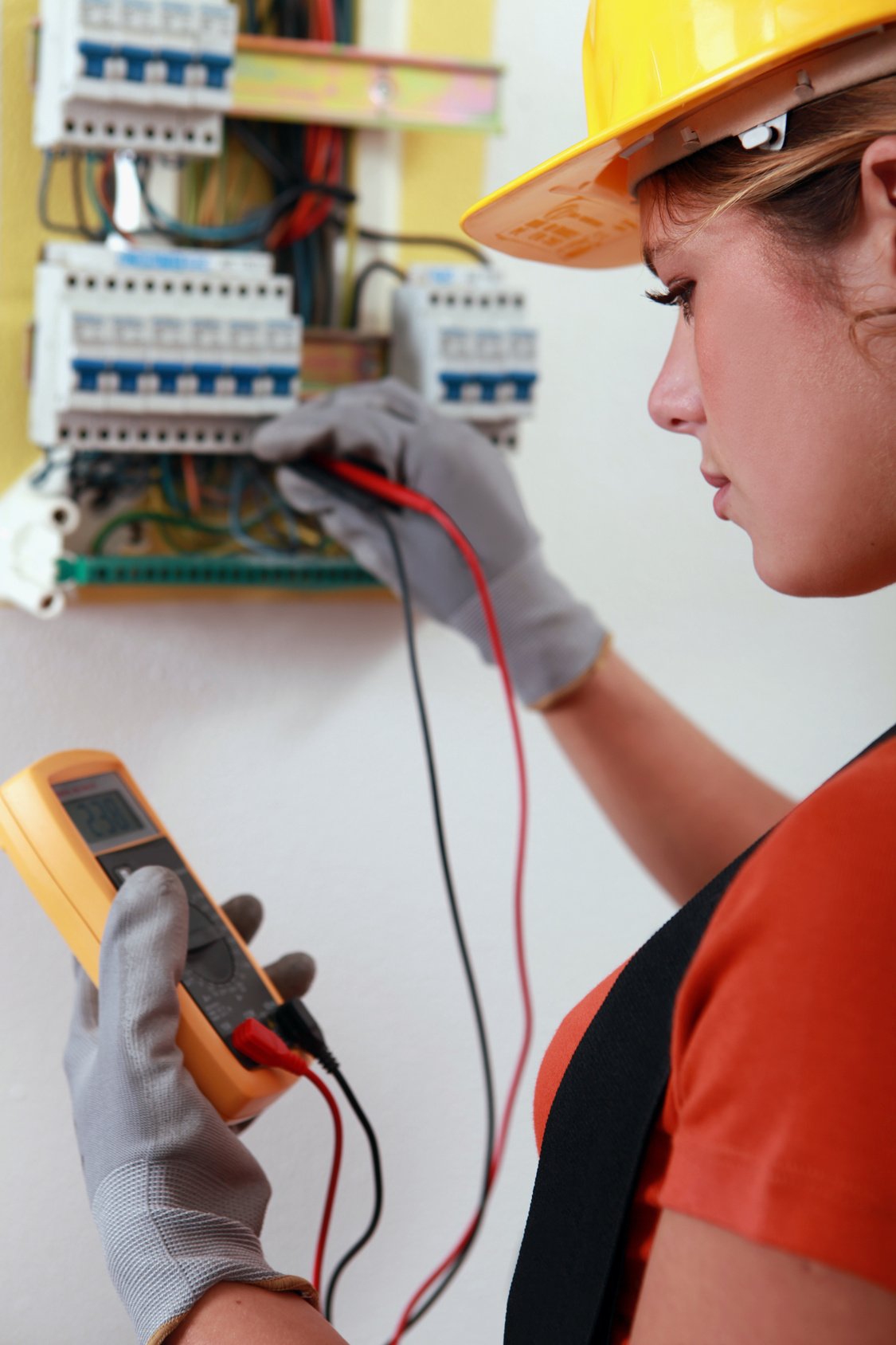 Female electrician checking the wiring on a fusebox